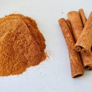 Close-up of aromatic cinnamon sticks and cinnamon powder on a white surface.